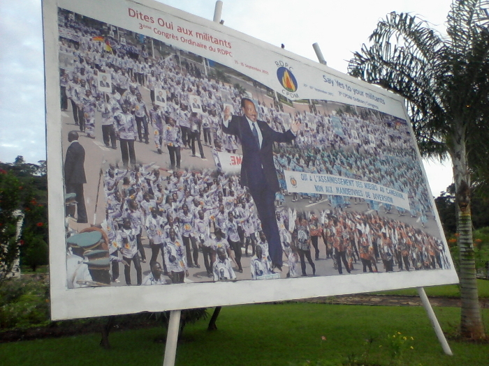 Ein Propaganda-Poster. Das Poster wurde 2011 anlässlich eines Kongresses der regierenden Staatspartei RDPC aufgestellt. Übergroß im Vordergrund: Paul Biya. Bildquelle: Foto des Autors.