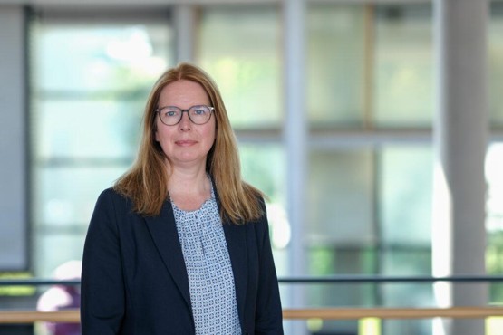 Porträtfoto von Kathrin Brannemann mit hellblauer Bluse, dunkelblauem Jacket, Brille und blonden, mittellangen Haaren.