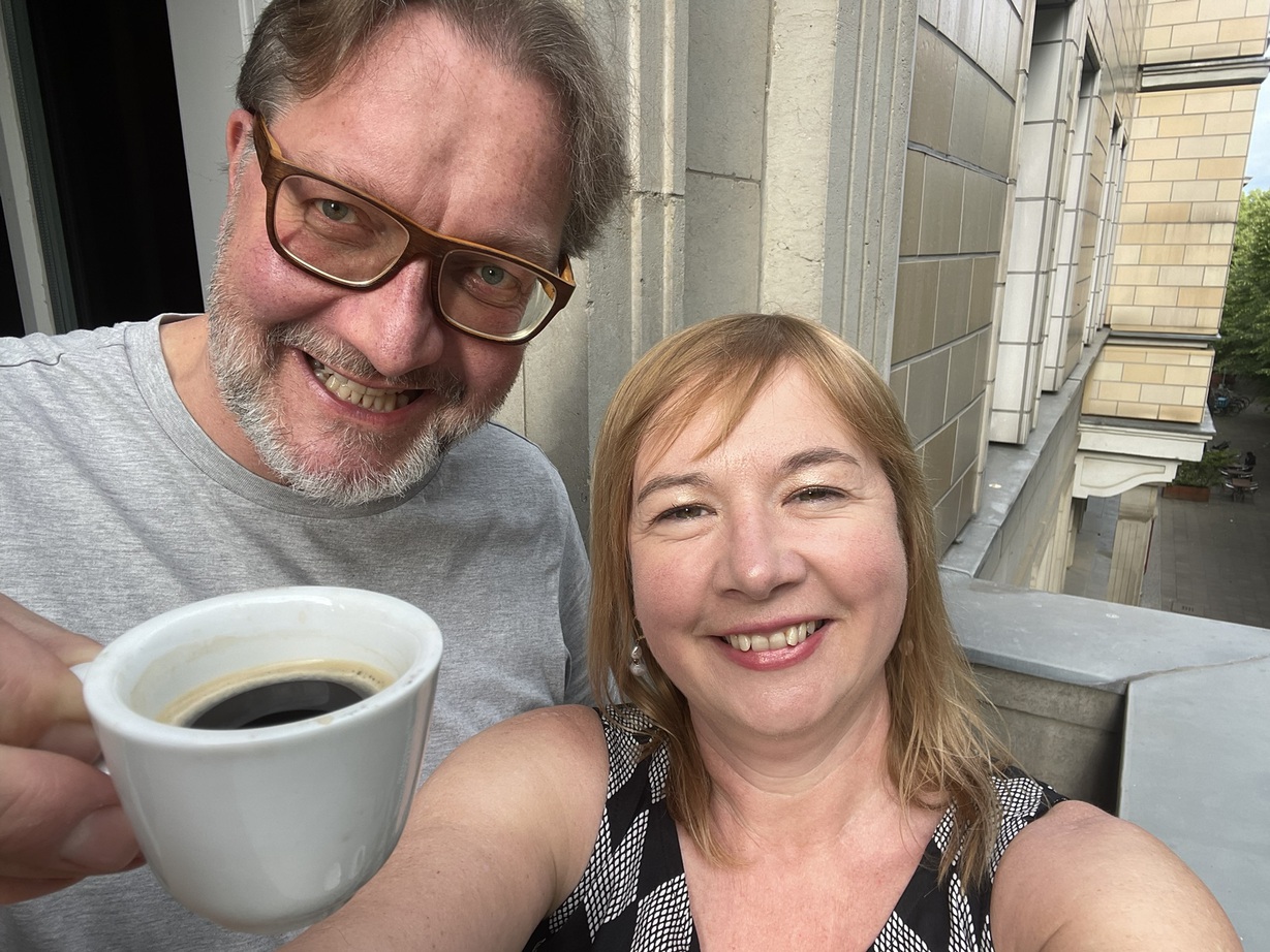 Ein Selfie von Dirk Wissen und Linda Freyberg. Beide lächeln in die Kamera und Dirk Wissen hält eine Tasse mit Espesso vor die Linse.